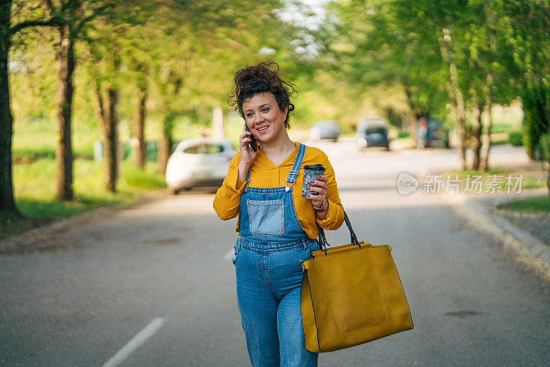 一个轻松的卷发女人一边走一边打电话。