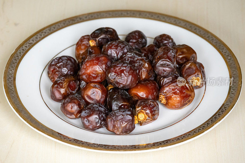 美味的干枣棕榈水果或库尔玛在木制背景上的白色盘子。在孟加拉国当地，它被称为Khejur。枣富含纤维和抗氧化剂。