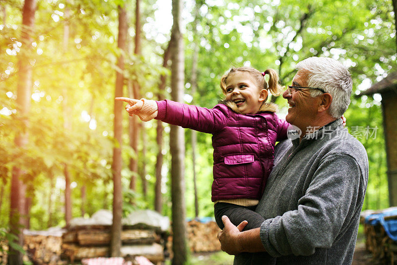 小女孩在森林里给爷爷看东西。