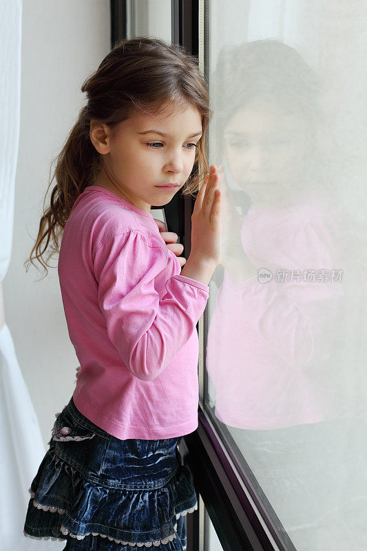 悲伤的小女孩望着窗外