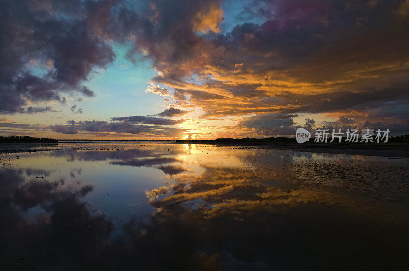 日出时热带海岸泻湖上戏剧性的天空反射