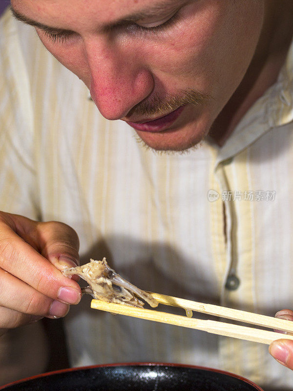 日本东京，一名男子正在吃汤里的鲜鱼。
