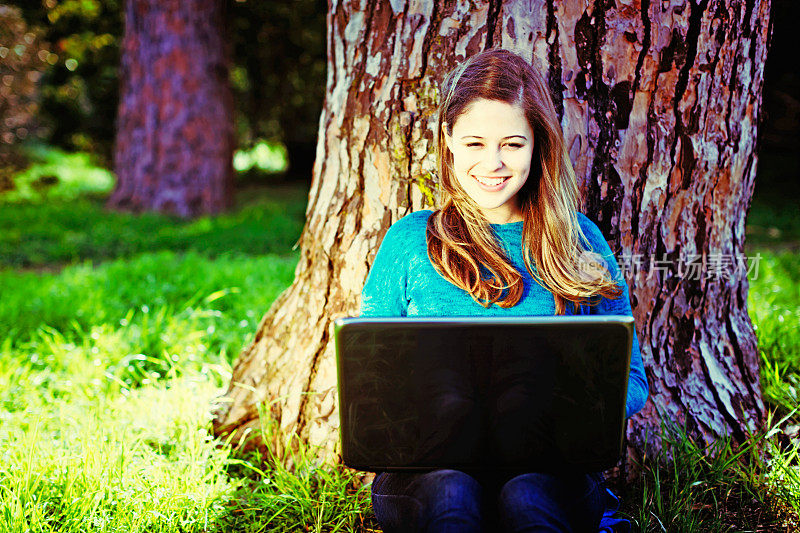 无纸化交流拯救树木:年轻美女与笔记本电脑树下