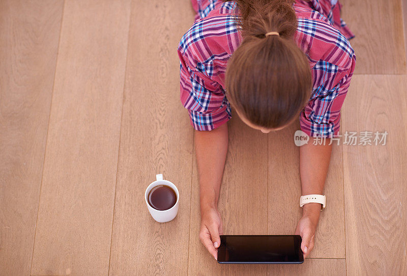 年轻女子一边喝着咖啡一边用着平板电脑