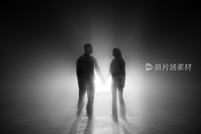 一对夫妇牵着手走向光明的剪影