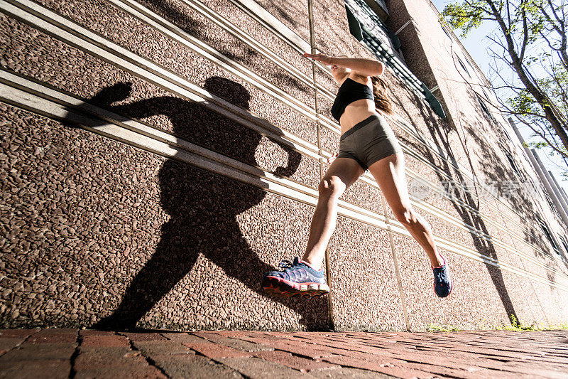 健身的女人在城市里对着墙跑