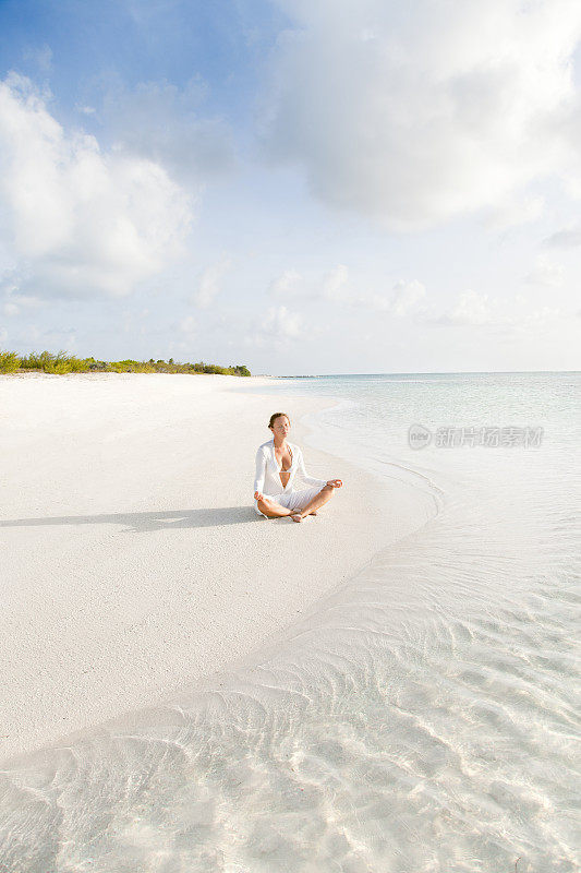 一个在加勒比海海滩上练习瑜伽的女人