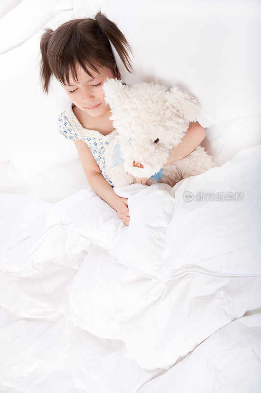 小女孩和泰迪熊一起睡觉