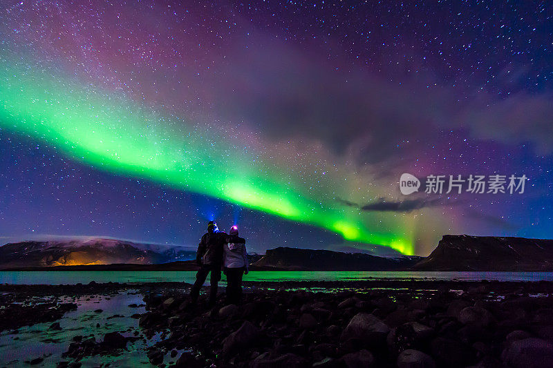 这对年轻情侣在冰岛的北极光下拥抱