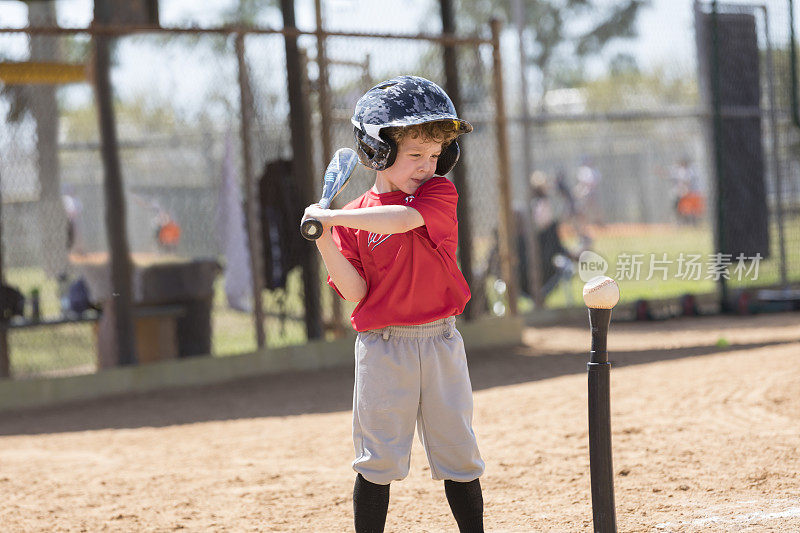 4岁的小男孩准备在一场T-Ball游戏中挥动棒球棒