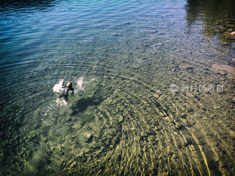 一个孩子试图在冰冷的山湖里游泳