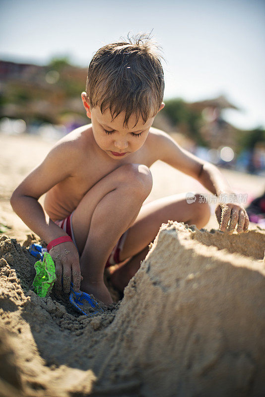 小男孩在海滩上建沙堡