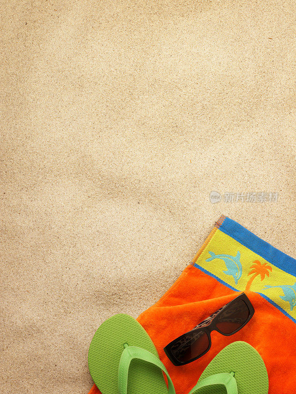 太阳镜和沙滩浴巾躺在沙滩上