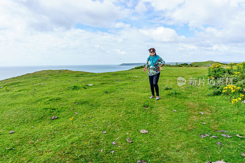 西班牙老妇人走在遥远的海岸岬角上