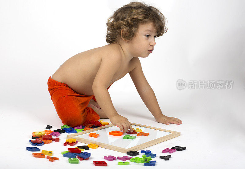 小男孩在玩五颜六色的字母