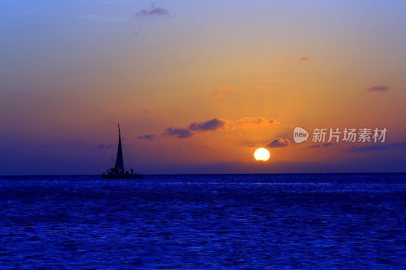 加勒比碧绿的海滩天堂，帆船，戏剧性的阳光明媚的日落