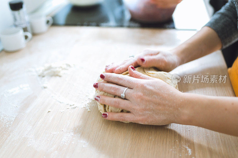 年轻漂亮的女人在厨房里做面团