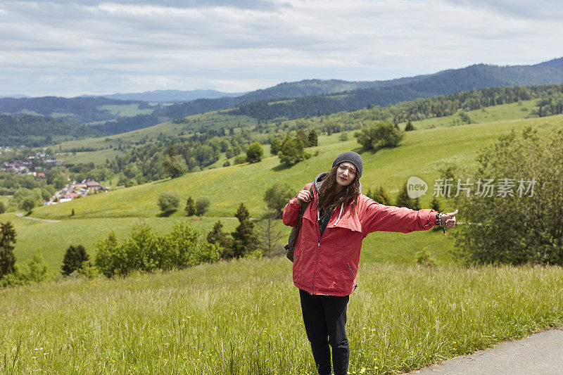 女人搭便车旅行。春天的山