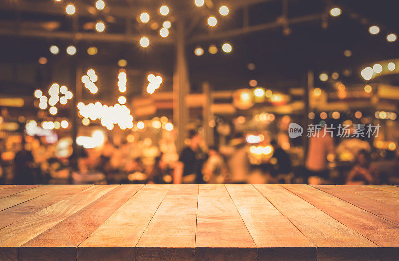 木桌与模糊的灯光散景在黑暗的夜晚咖啡馆