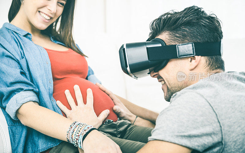 年轻夫妇与怀孕的女人有乐趣与vr眼镜技术头戴式耳机-快乐的人与男人丈夫使用虚拟现实设备在妻子的肚子上-可穿戴技术概念-清楚的古董过滤器