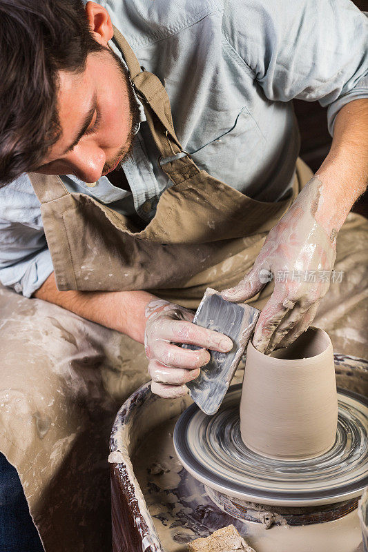 陶艺，工作室，陶艺艺术概念-年轻的男性雕刻一些新的器皿与手，工具，手指和水，人的工作与陶工的车轮和原始火粘土，墨西哥，西班牙，拉丁美洲