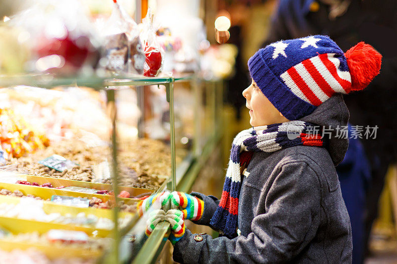 一个小男孩在圣诞市场上吃着苹果糖