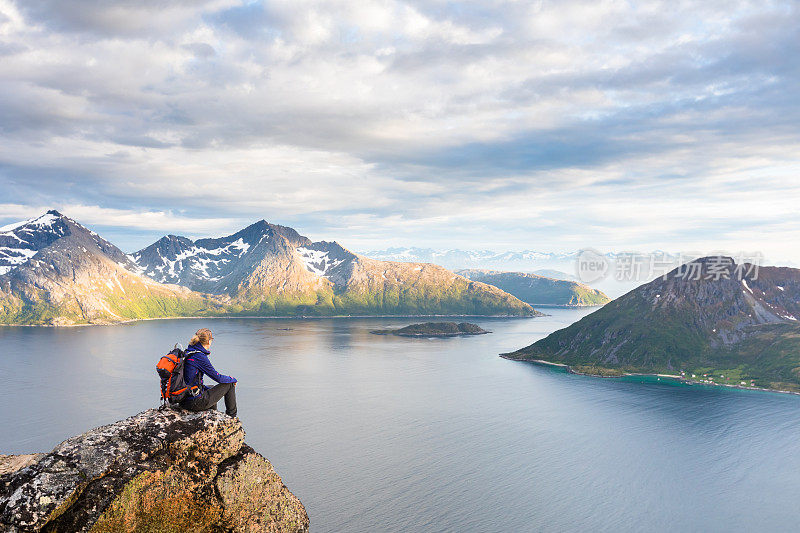 女徒步旅行者看着美丽的挪威峡湾风景