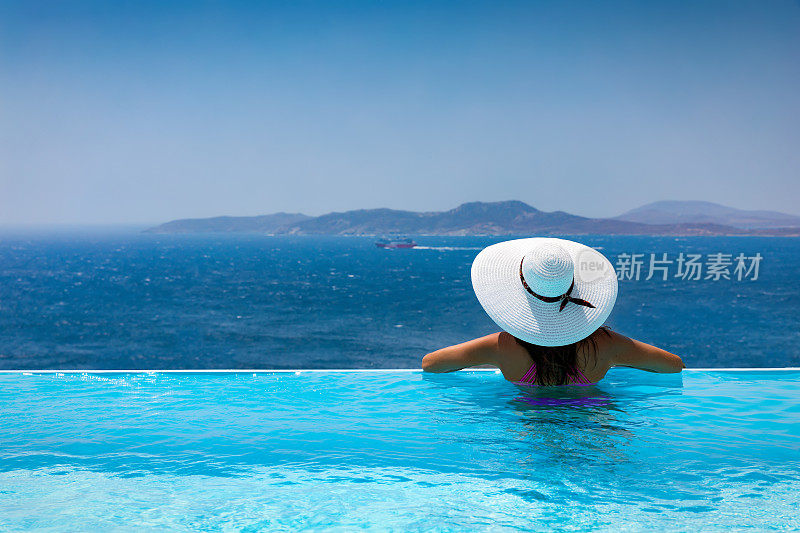 迷人的女人享受从游泳池到地中海的景色