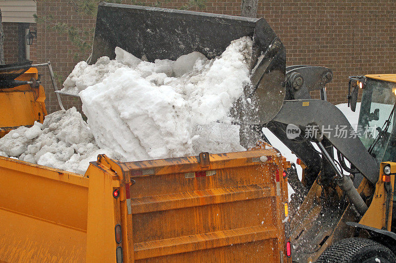 一辆黄色的自卸卡车正在倾倒积雪