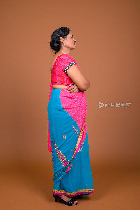 工作室拍摄的成熟美丽的印度妇女穿着印度传统服装莎丽在彩色的背景