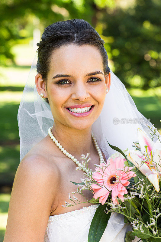一个美丽的新娘与花束在公园的特写肖像