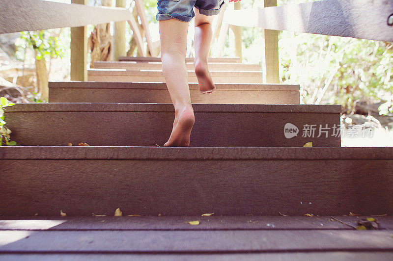 女孩全速跑上户外的木台阶