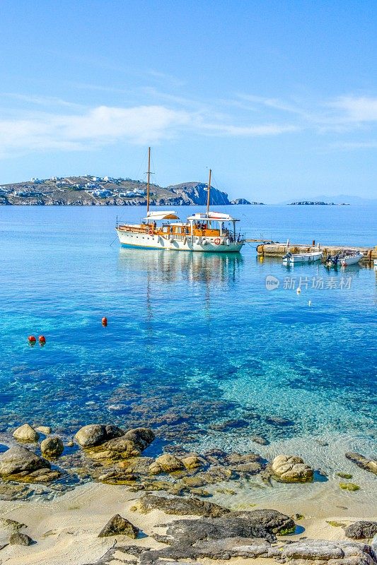 夏日白天，传统的木制游艇载着游客从米科诺斯岛前往提洛斯岛