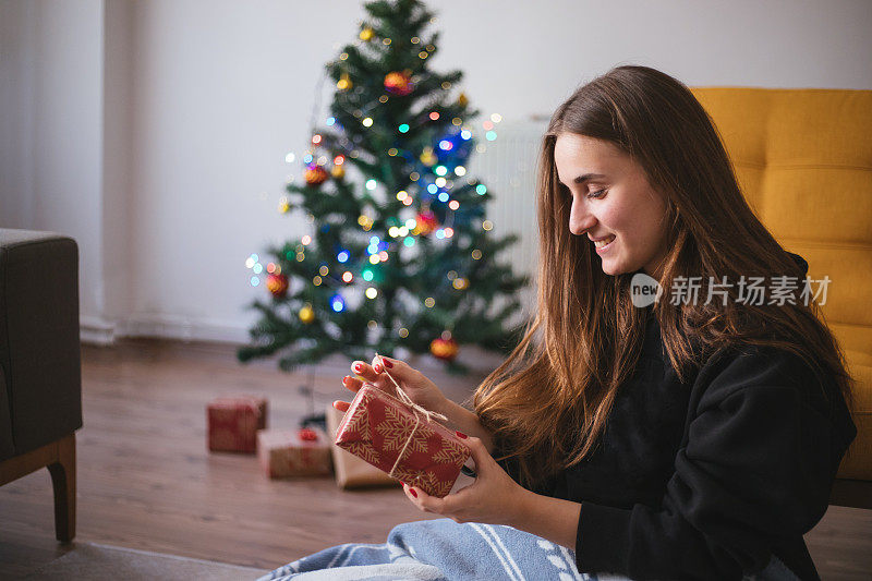 女人在圣诞树前拿着礼物