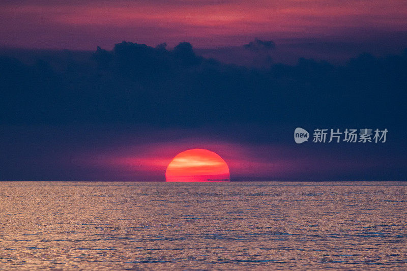 海上史诗般的日落。巨大的太阳掠过海洋。