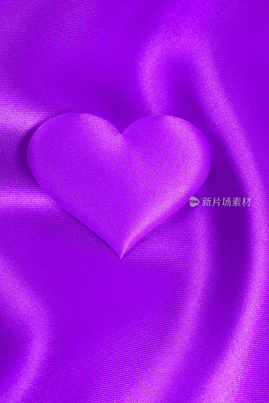 浪漫的背景(紫色绸缎上的紫色纺织心)