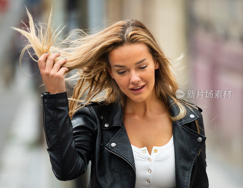 金发酷女人走在街上，玩弄头发