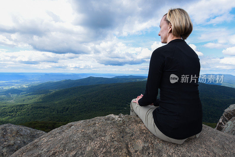 年轻的女子站在山顶，望着地平线