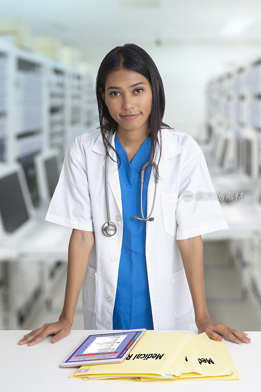 女医生站着，桌上放着病历夹和写字板。