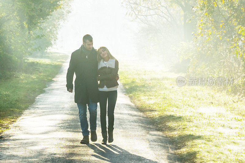 一对年轻夫妇漫步在秋日的阳光下