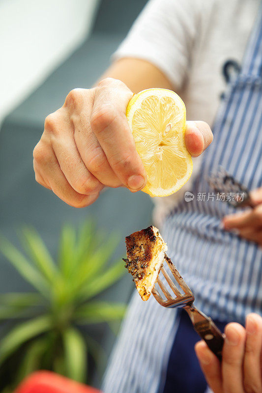 男性双手挤柠檬汁到一片烤阿根廷五花肉上的特写