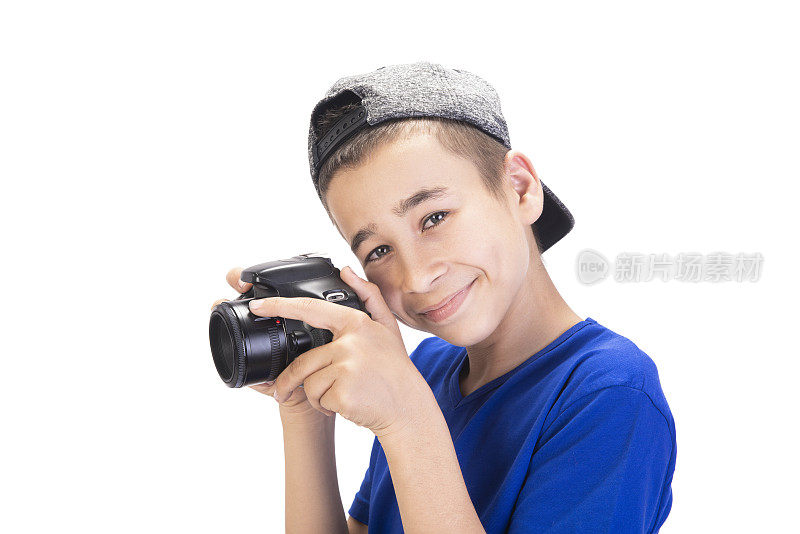 肖像快乐的十几岁的男孩拿着数码相机，看着相机与内容微笑对白色的背景