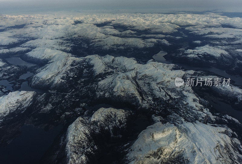 乘客从飞机上俯瞰挪威的峡湾，山上覆盖着积雪