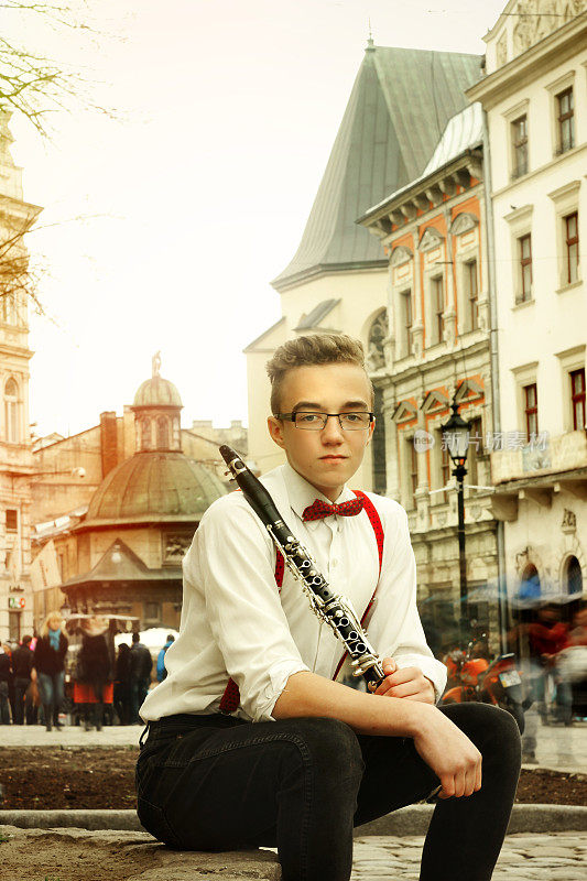 时尚潮人坐在和拿着单簧管在欧洲城市利沃夫老中心