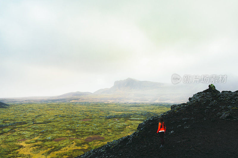 女游客在冰岛山顶欣赏风景优美的火山景观