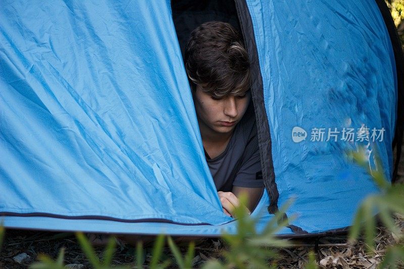 照片上的男孩在拉他的露营帐篷的拉链