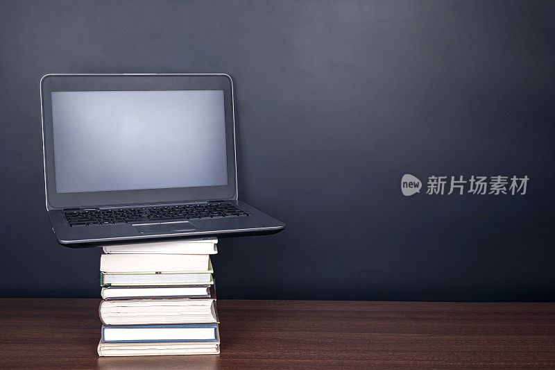电子学习:课桌上的书本和笔记本电脑，并配有黑板