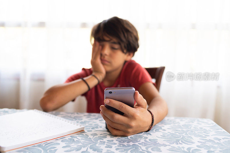拉丁裔青春期前男孩厌倦了用智能手机