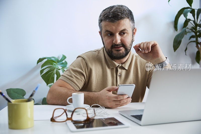 一个年轻人在他的家庭办公室里对着电脑说话