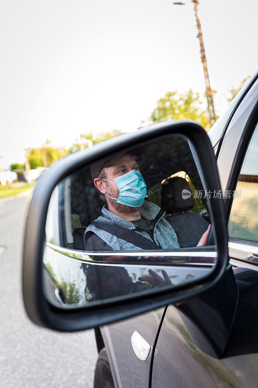 汽车司机戴着防护面罩检查他的镜子
